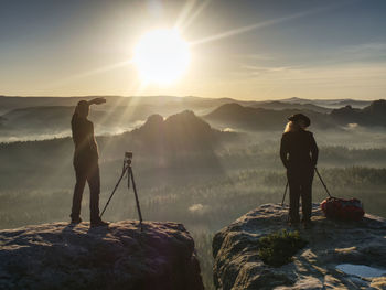 Two hikers taking pictures and talk on top of mountain. photographers with gear on top of mountain
