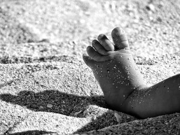 Low section of child lying on sand