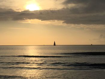 Silhouette of sailboat in sea during sunset