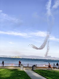 People at seaside against sky