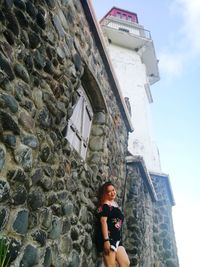 Low angle portrait of woman standing against building