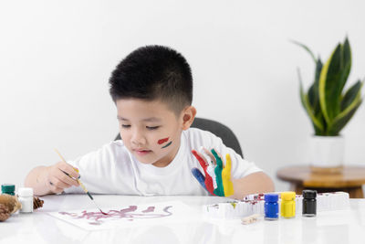 Boy looking away against white table