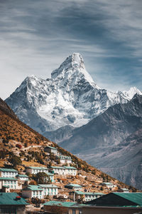 Aerial view of townscape by snowcapped mountain against sky