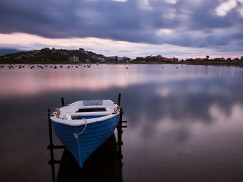 Sailboats moored in lake at sunset