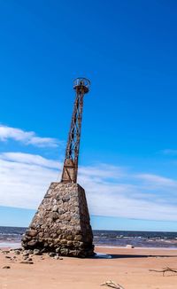 Traditional windmill on beach against blue sky