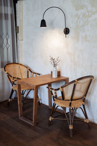 Empty chairs and table against wall at restaurant