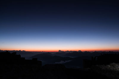 Silhouette mountains against clear sky at sunset