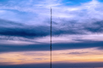 Low angle view of silhouette electricity pylon against dramatic sky