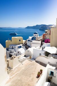 Scenic view of sea and buildings against clear blue sky