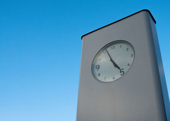 Low angle view of clock against blue sky