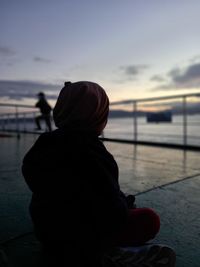 Rear view of silhouette woman looking at sea during sunset