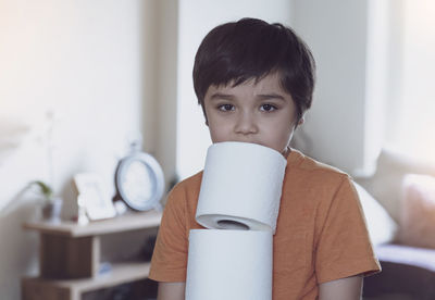 Portrait of boy holding toilet papers at home