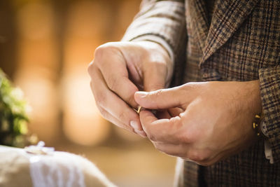 Midsection of bridegroom holding ring during wedding ceremony