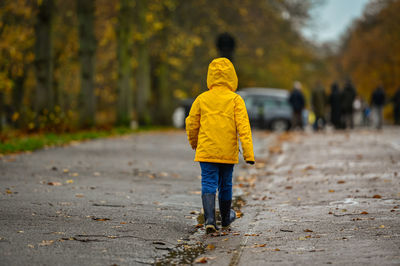 Rear view of man walking on yellow umbrella