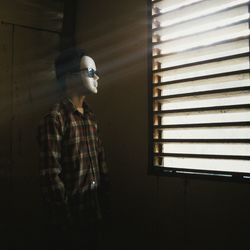 Man wearing mask standing by window