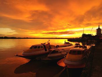 Boats moored on sea against sky during sunset