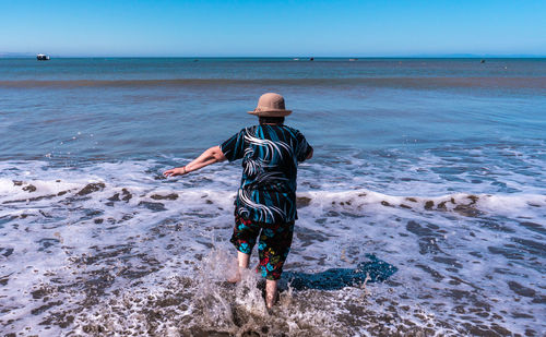 Rear view of person on beach against sky