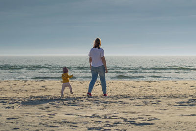 Rear view of woman on beach against sky