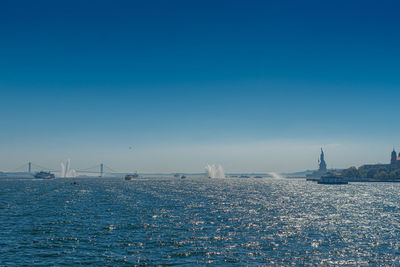 Sailboats in sea against clear blue sky