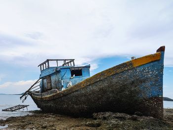 Abandoned boat on beach against sky
