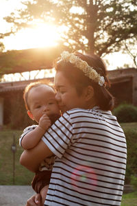 Mother holding baby at sunset