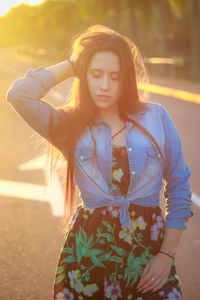 Young woman with hand in hair standing on road