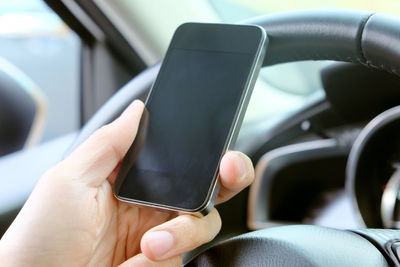 Cropped hand of person using mobile phone in car