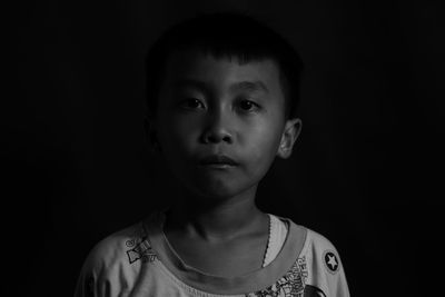 Portrait of cute boy against black background