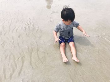 High angle view of boy playing on sand at beach