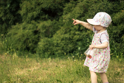 Girl standing on grass against trees