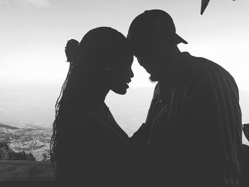 Silhouette couple romancing against sky