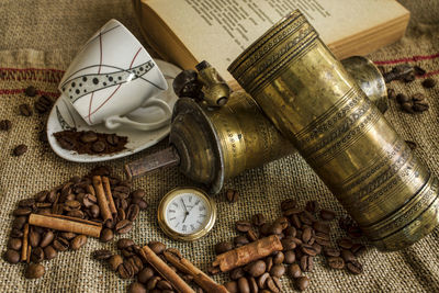Close-up of roasted coffee beans with book and pocket watch on sack