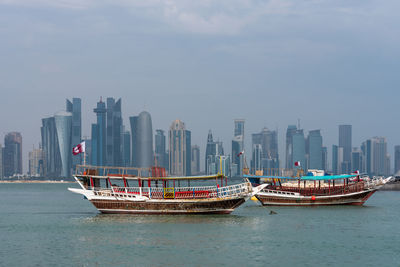 Boats in sea against sky in city