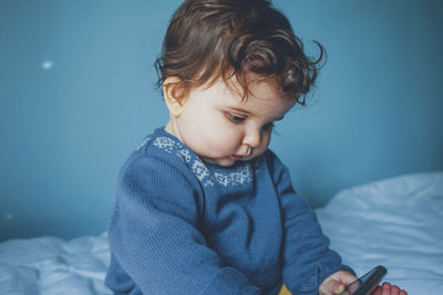 Cute boy looking away while relaxing on bed