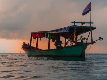 Fishing boat in sea against sky during sunset