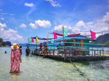 Rear view of woman with umbrella on sea against sky