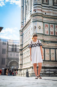 Full length of woman walking against buildings in city