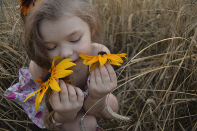 Low angle view of girl holding yellow flowering plants