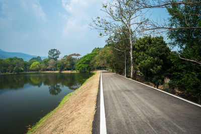 Empty road by trees against sky