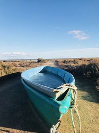 Boat moored on land against blue sky