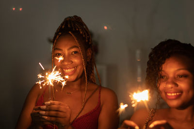 Portrait of woman blowing burning at night