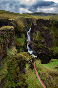 Scenic view of waterfall against cloudy sky