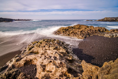 Scenic view of rocks on beach against sky