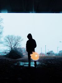 Rear view of silhouette man looking at camera against sky