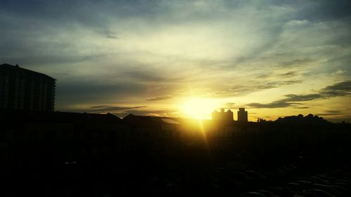 Silhouette cityscape against sky during sunset