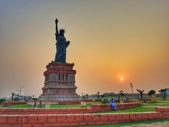 Statue of liberty replica against sky during sunset