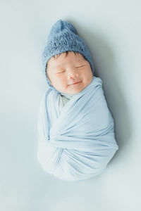 High angle view of cute baby sleeping against blue background