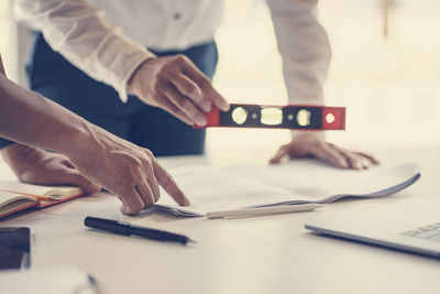 Midsection of man holding smart phone on table