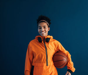 Portrait of young man standing against blue background
