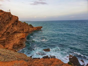 Rock formation on sea shore against sky